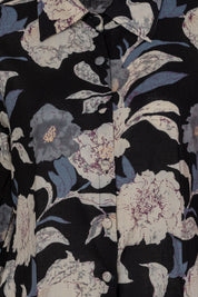 Black cotton shirt dress with bold floral and chevron print, featuring cream, blue, and purple tones, button front, and collar detail, close-up view