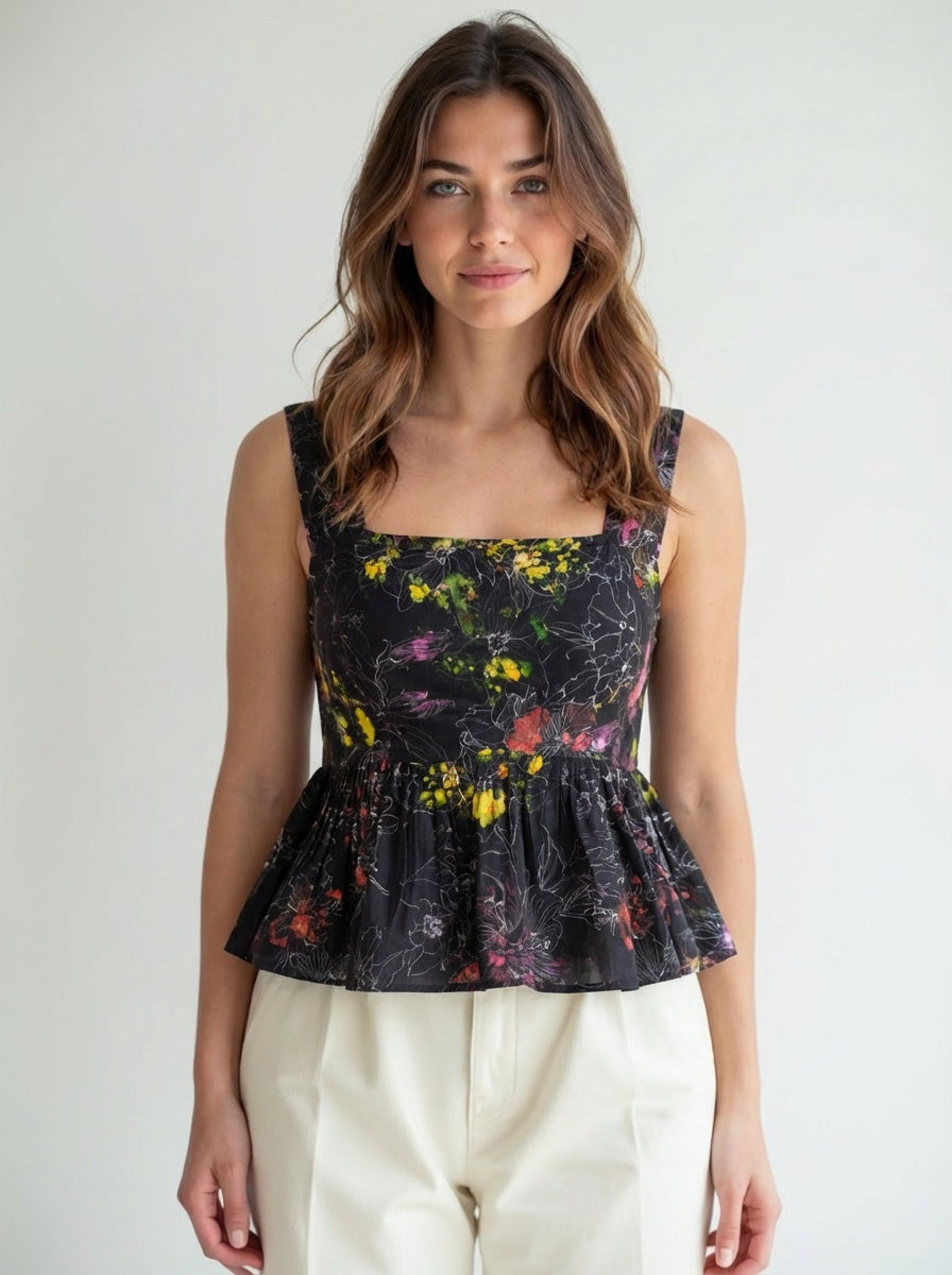 Woman wearing a floral peplum top against a plain background