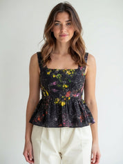 Woman wearing a floral peplum top against a plain background