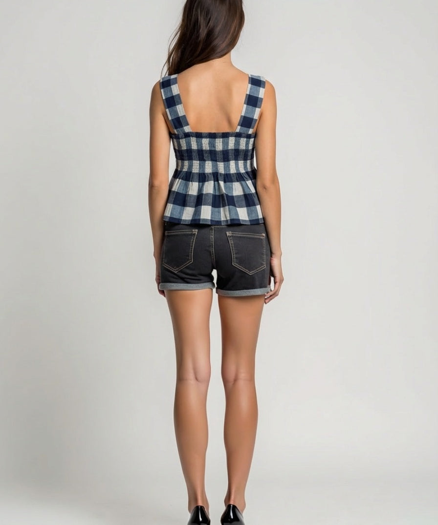 Person wearing a checkered top and denim shorts on a plain background