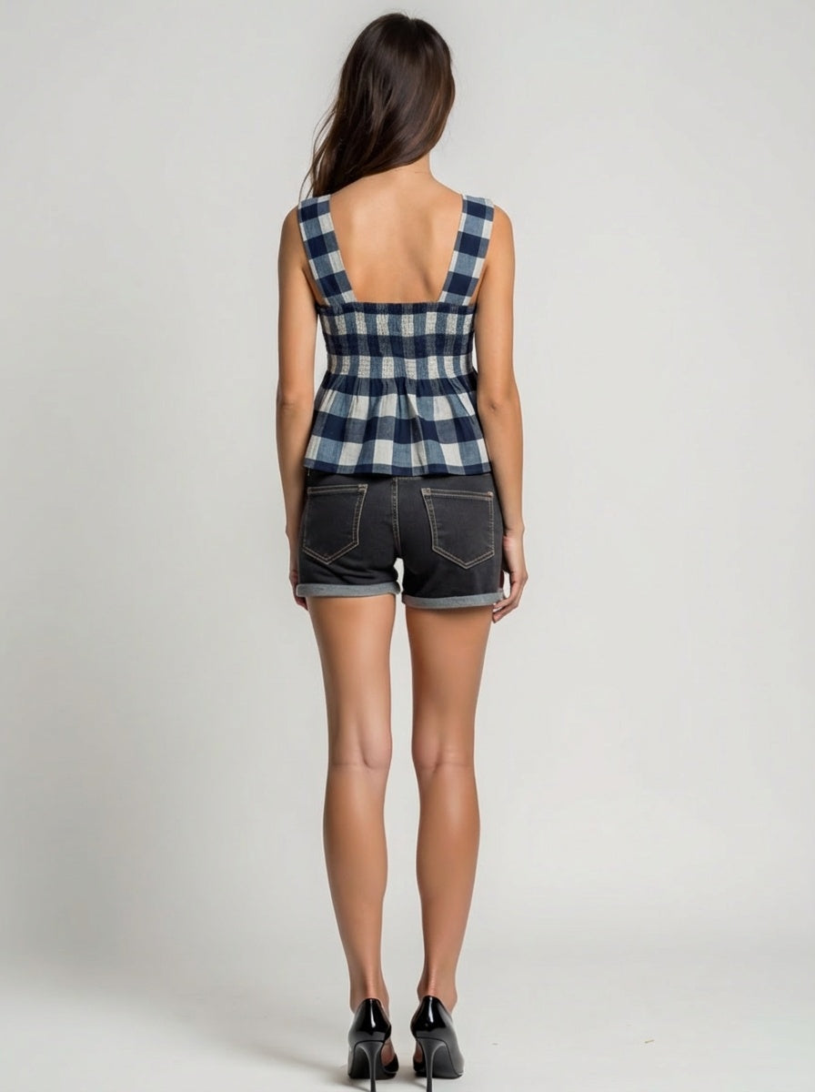 Person wearing a checkered top and denim shorts on a plain background