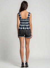 Person wearing a checkered top and denim shorts on a plain background