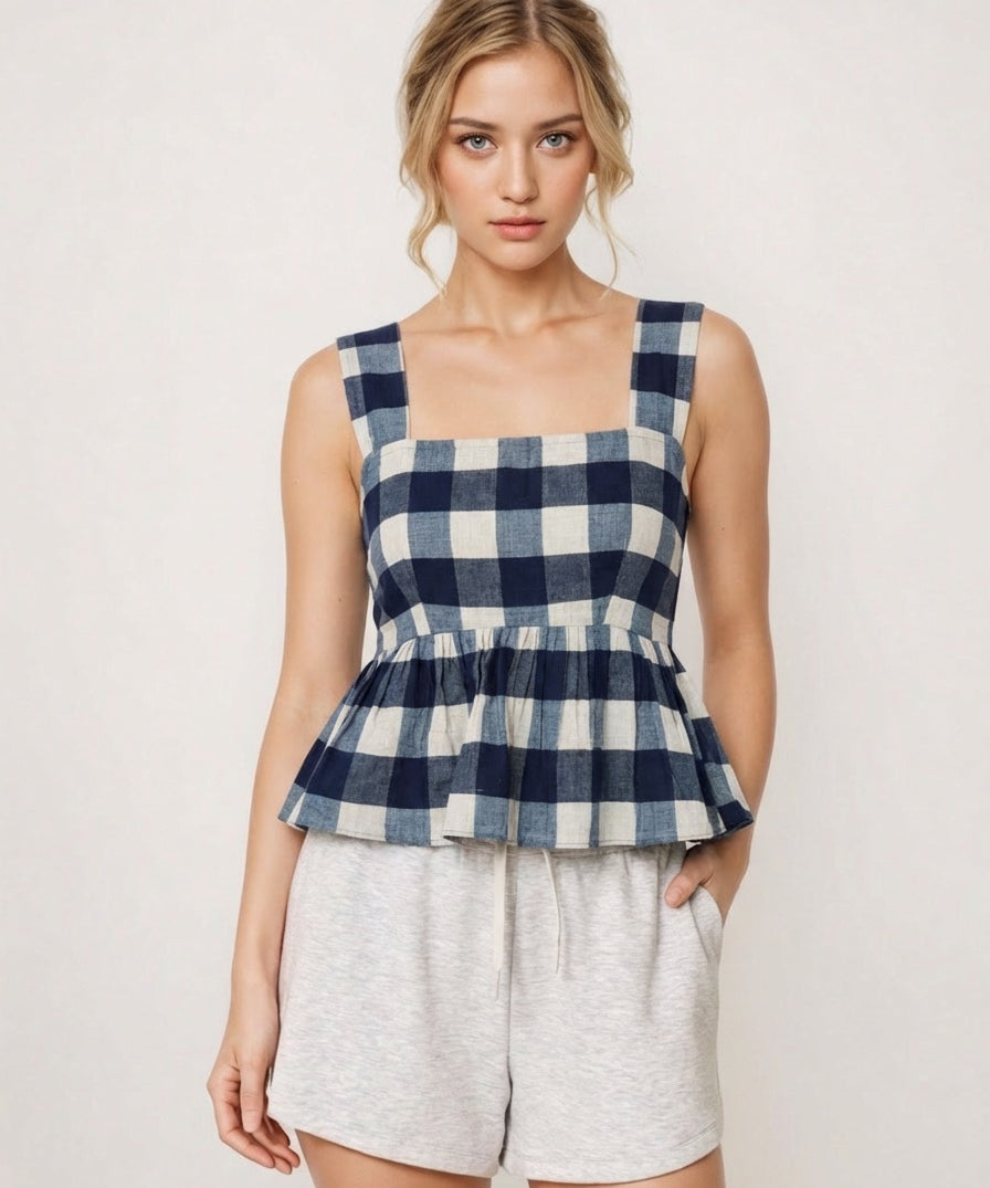Woman wearing a blue and white checkered top with gray shorts on a plain background