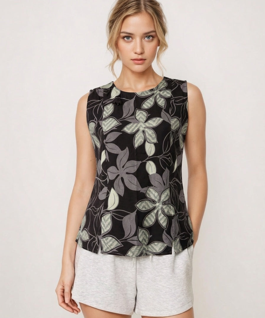 Woman wearing a sleeveless black floral top and white shorts on a light background