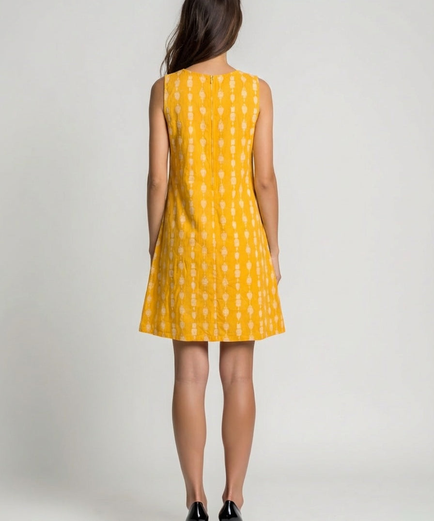 Woman wearing a yellow dress with a white pattern on a plain background