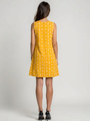 Woman wearing a yellow dress with a white pattern on a plain background