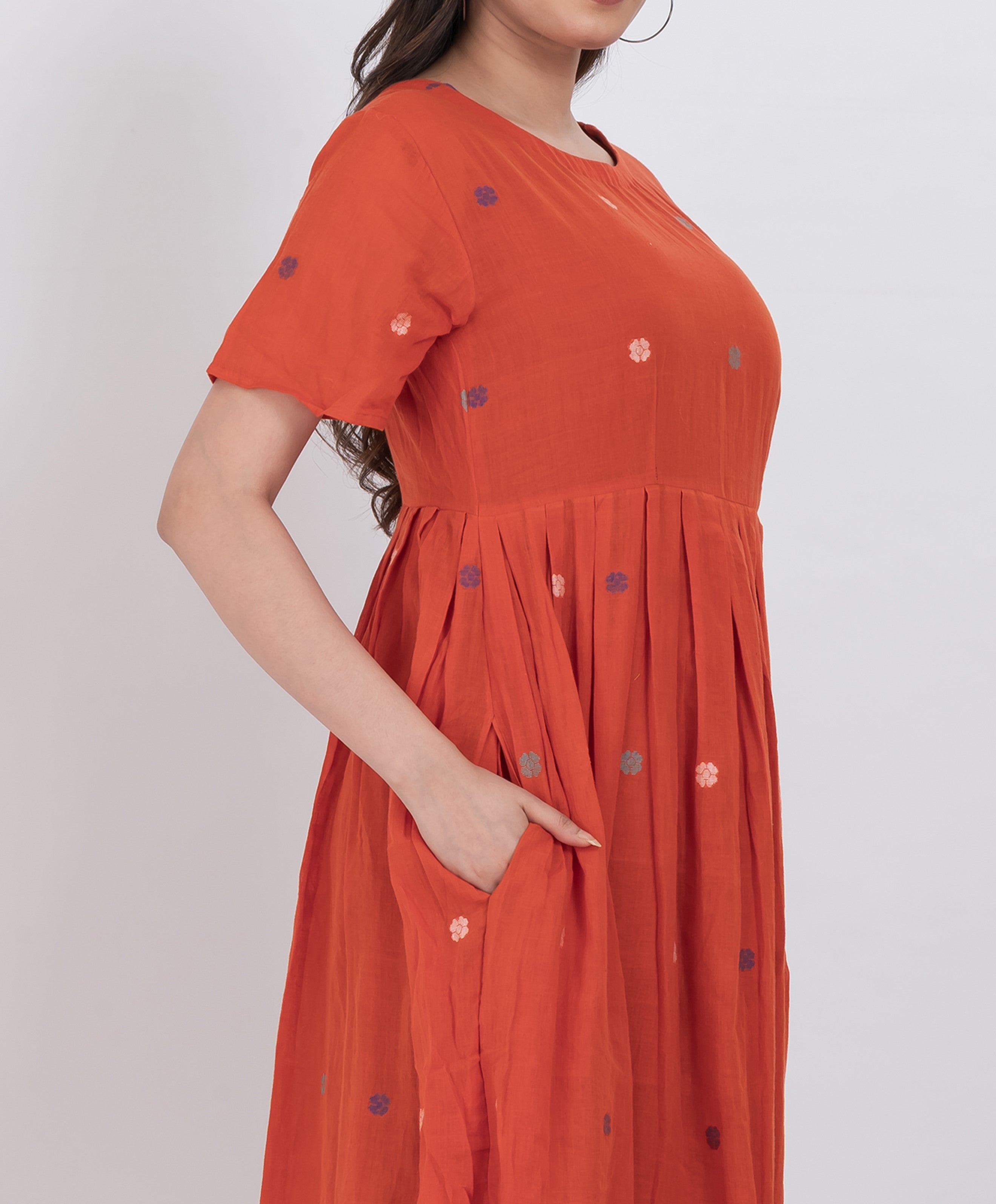  Casual handwoven cotton dress with floral embroidery and pleated A-line silhouette.