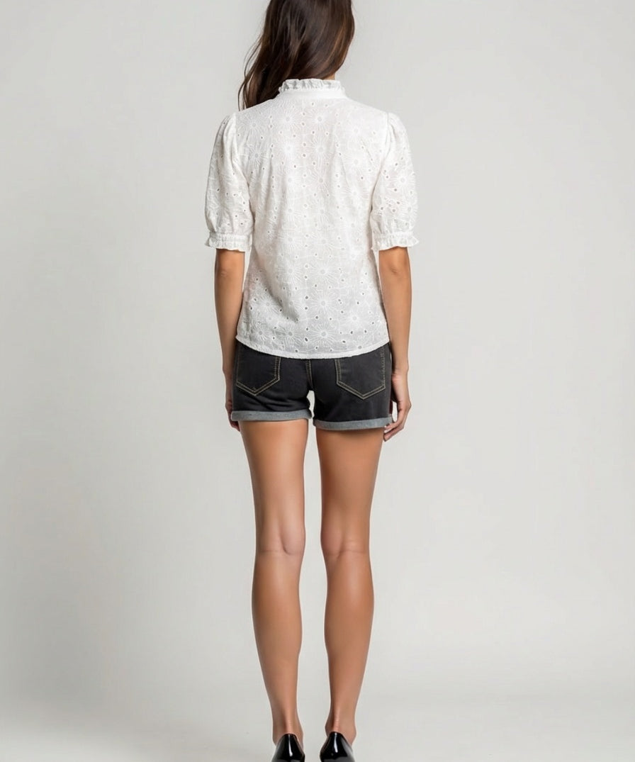 Person wearing a white patterned shirt and black shorts on a plain background