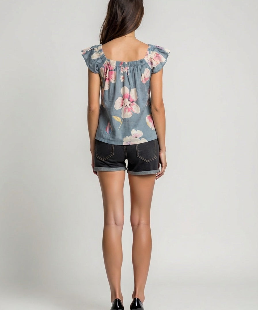Woman wearing a floral denim top and shorts on a plain background