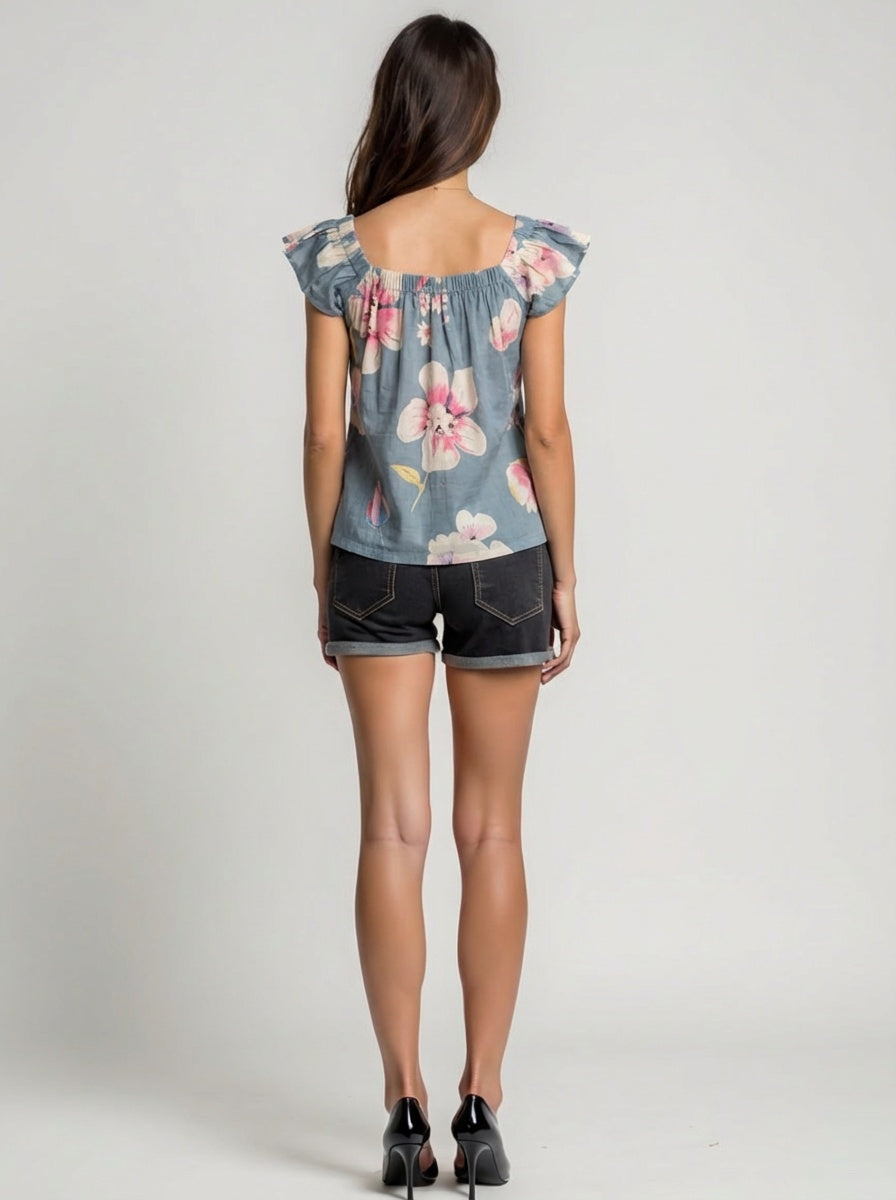 Woman wearing a floral denim top and shorts on a plain background