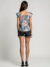 Woman wearing a floral denim top and shorts on a plain background
