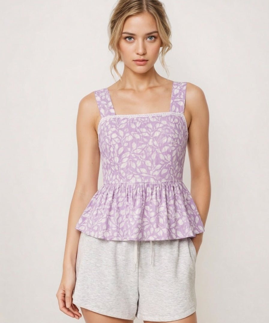 Woman wearing a purple floral peplum top and gray shorts on a white background