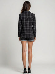 Person wearing a black and white checkered blazer and denim shorts on a plain background