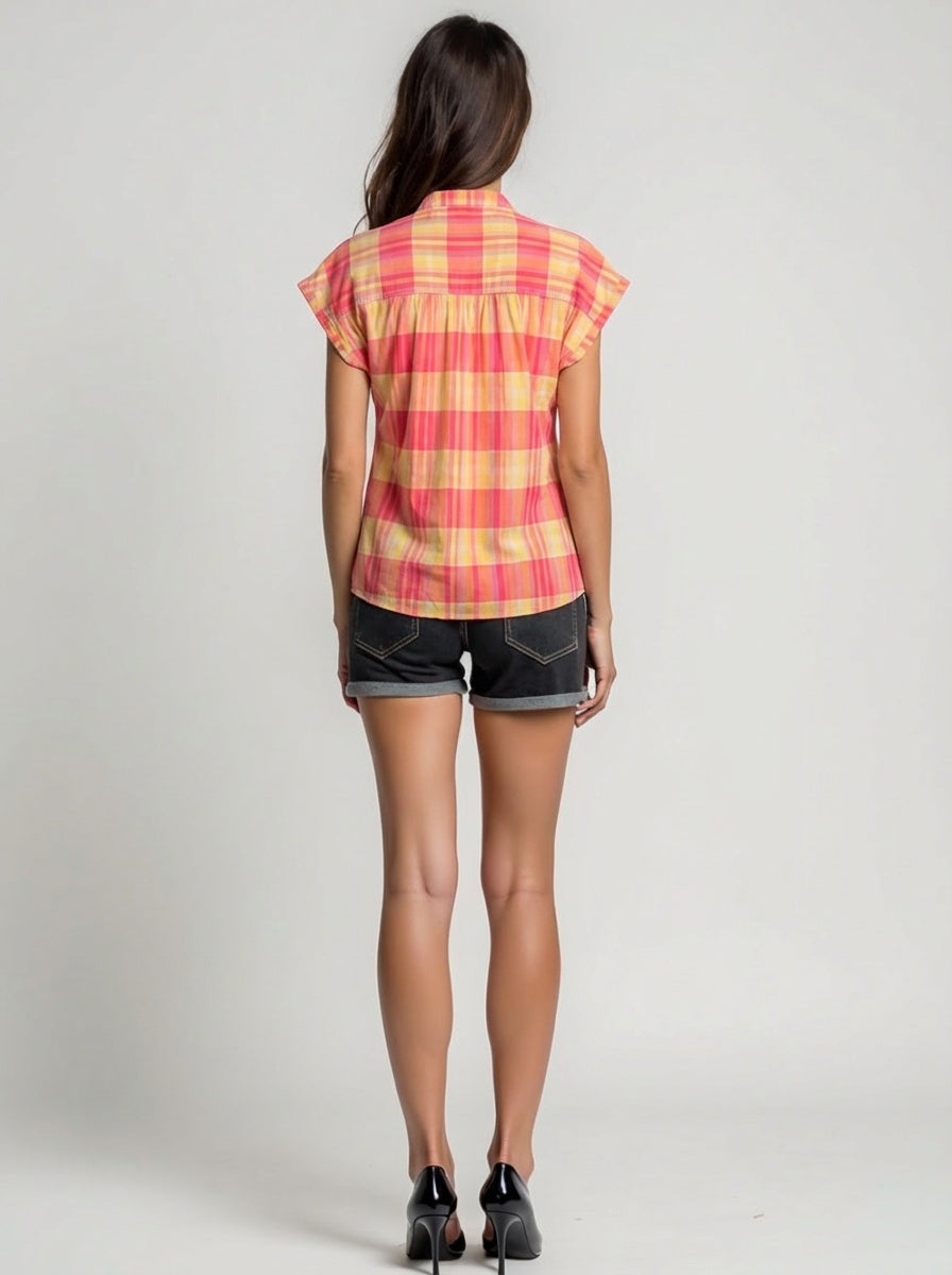 Woman wearing a red and yellow plaid shirt with black shorts on a gray background