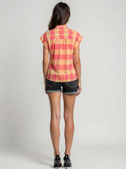 Woman wearing a red and yellow plaid shirt with black shorts on a gray background