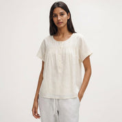 Woman wearing a white blouse and gray pants on a plain background