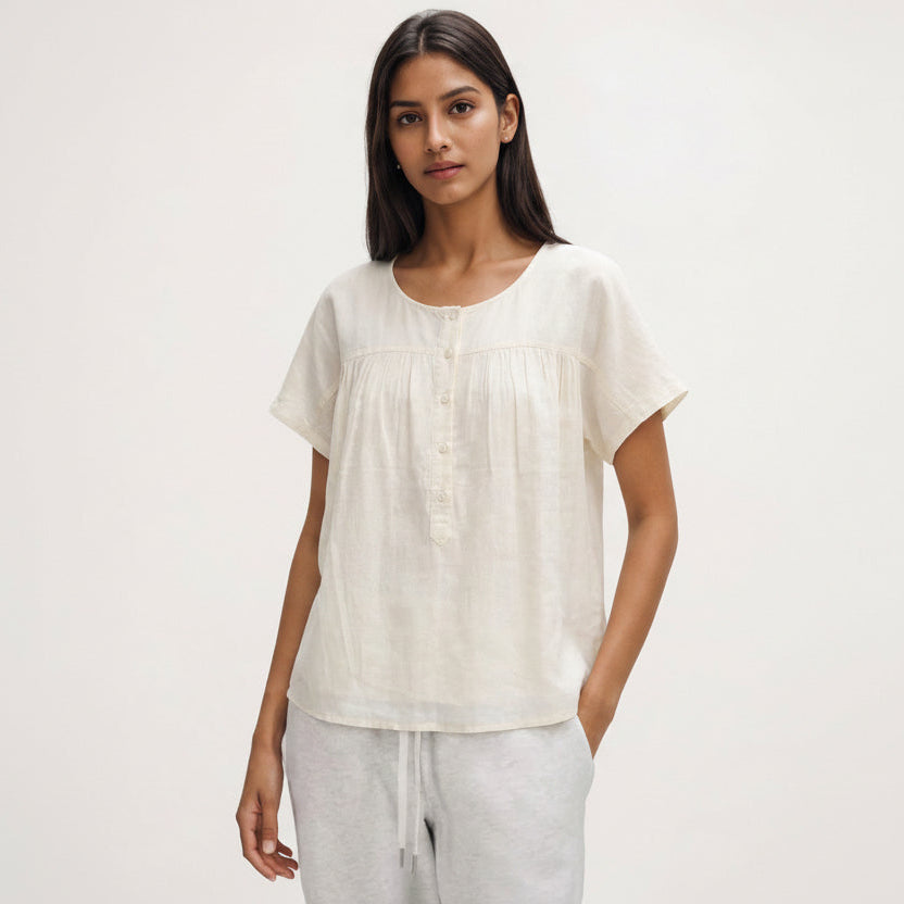 Woman wearing a white blouse and gray pants on a plain background