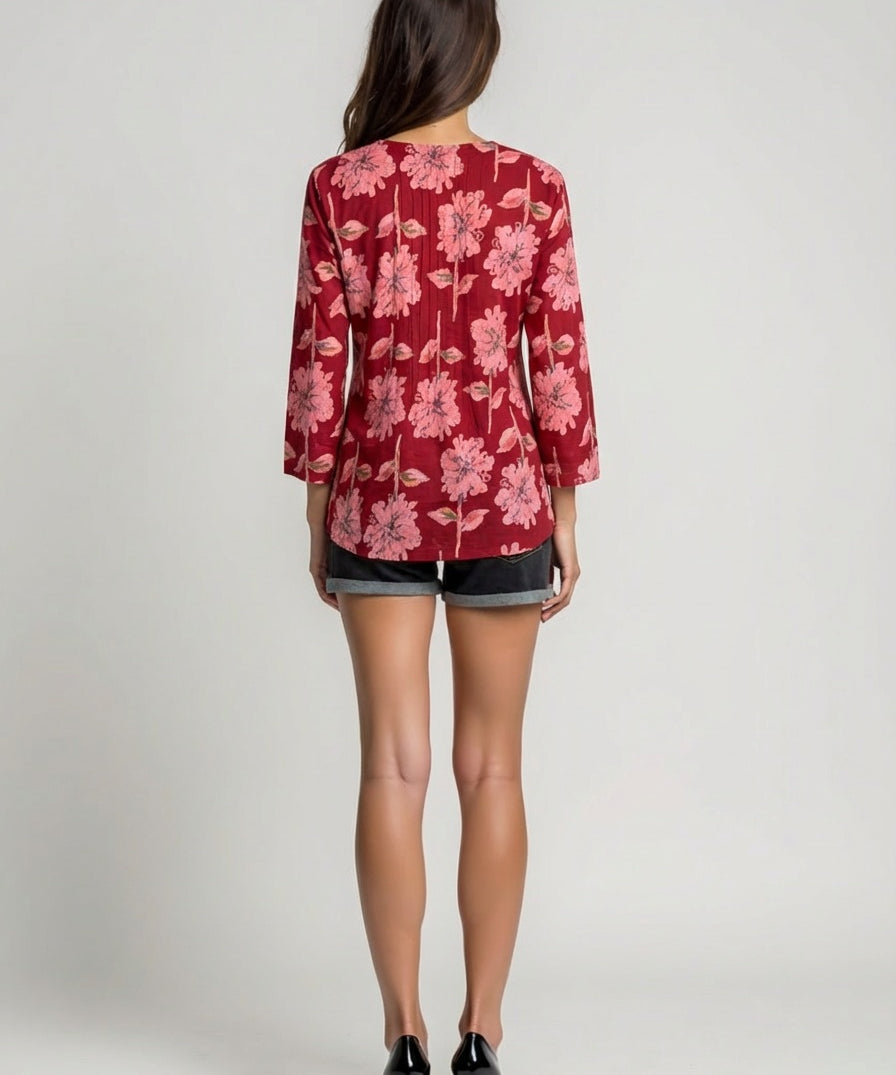 Person wearing a red floral blouse and black shorts on a plain background