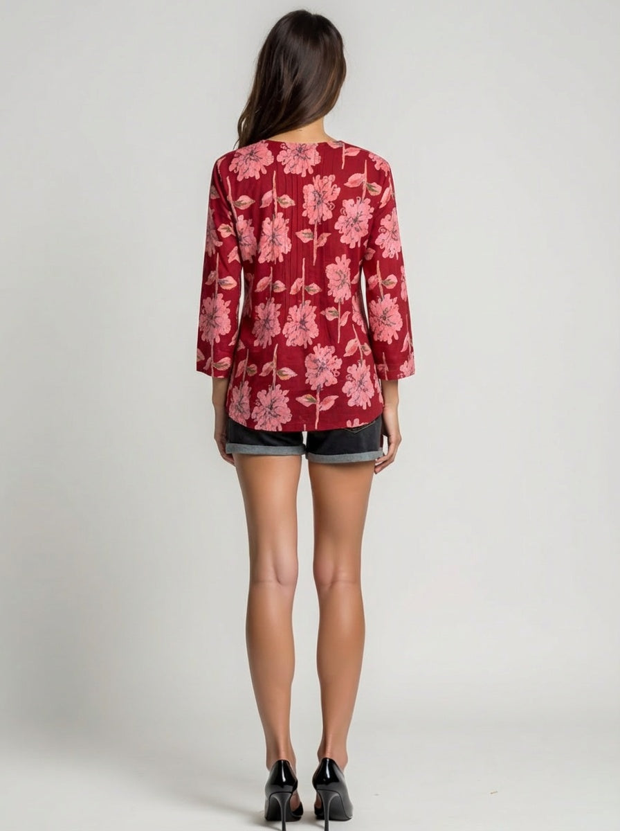 Person wearing a red floral blouse and black shorts on a plain background