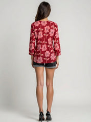 Person wearing a red floral blouse and black shorts on a plain background
