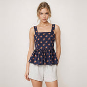Woman wearing a navy floral peplum top and light gray shorts on a white background