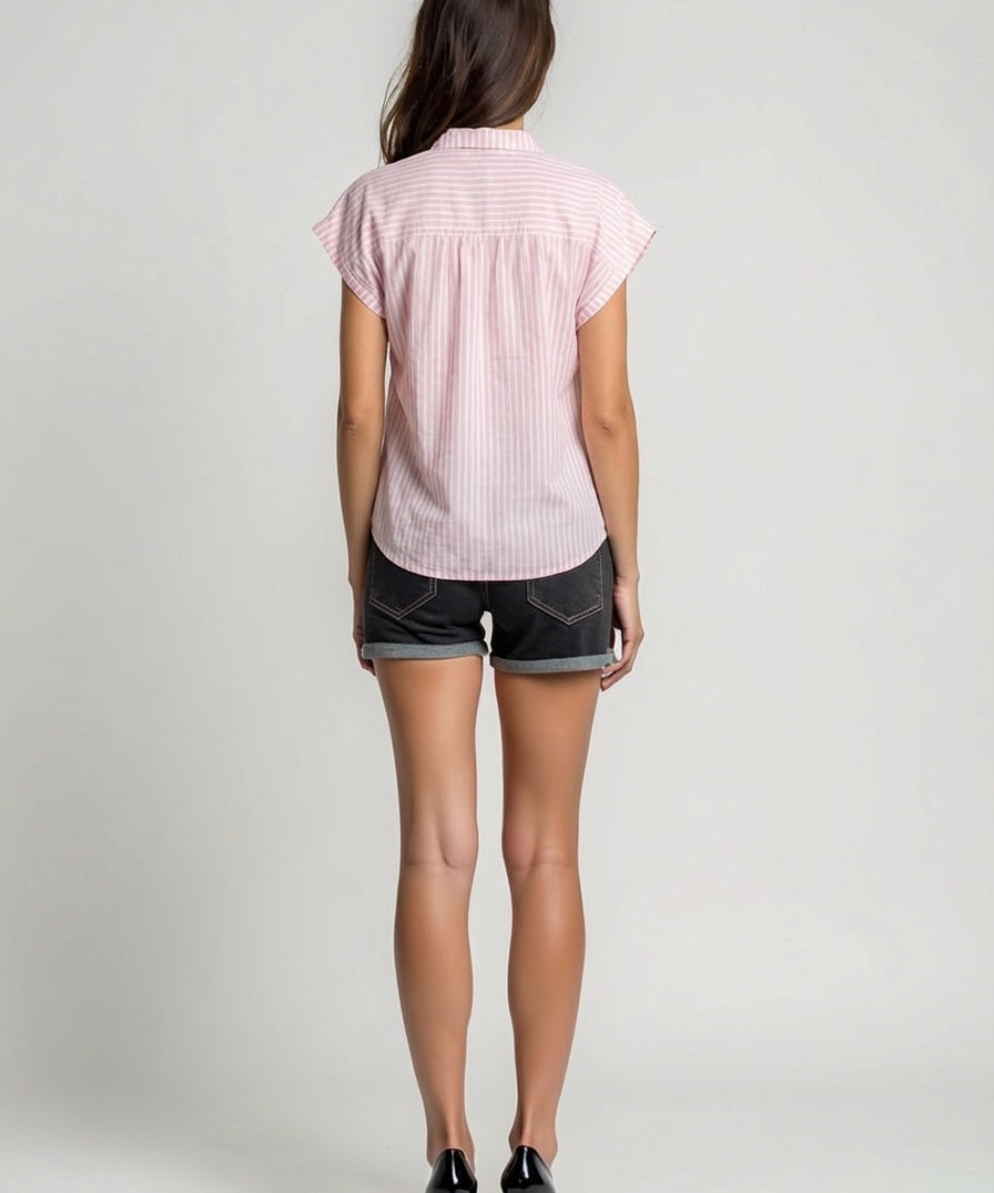 Person wearing a pink short-sleeve shirt and black shorts on a plain background