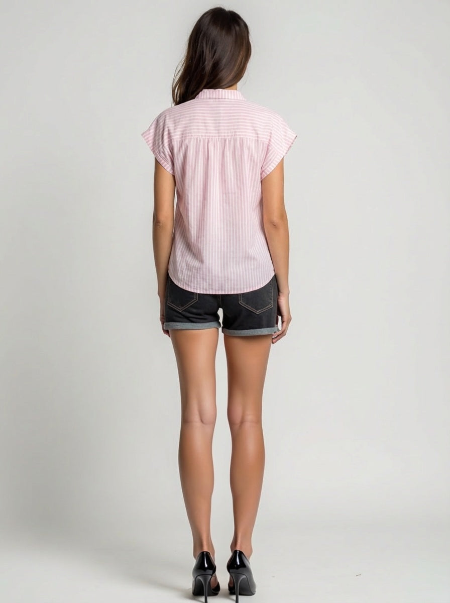 Person wearing a pink short-sleeve shirt and black shorts on a plain background