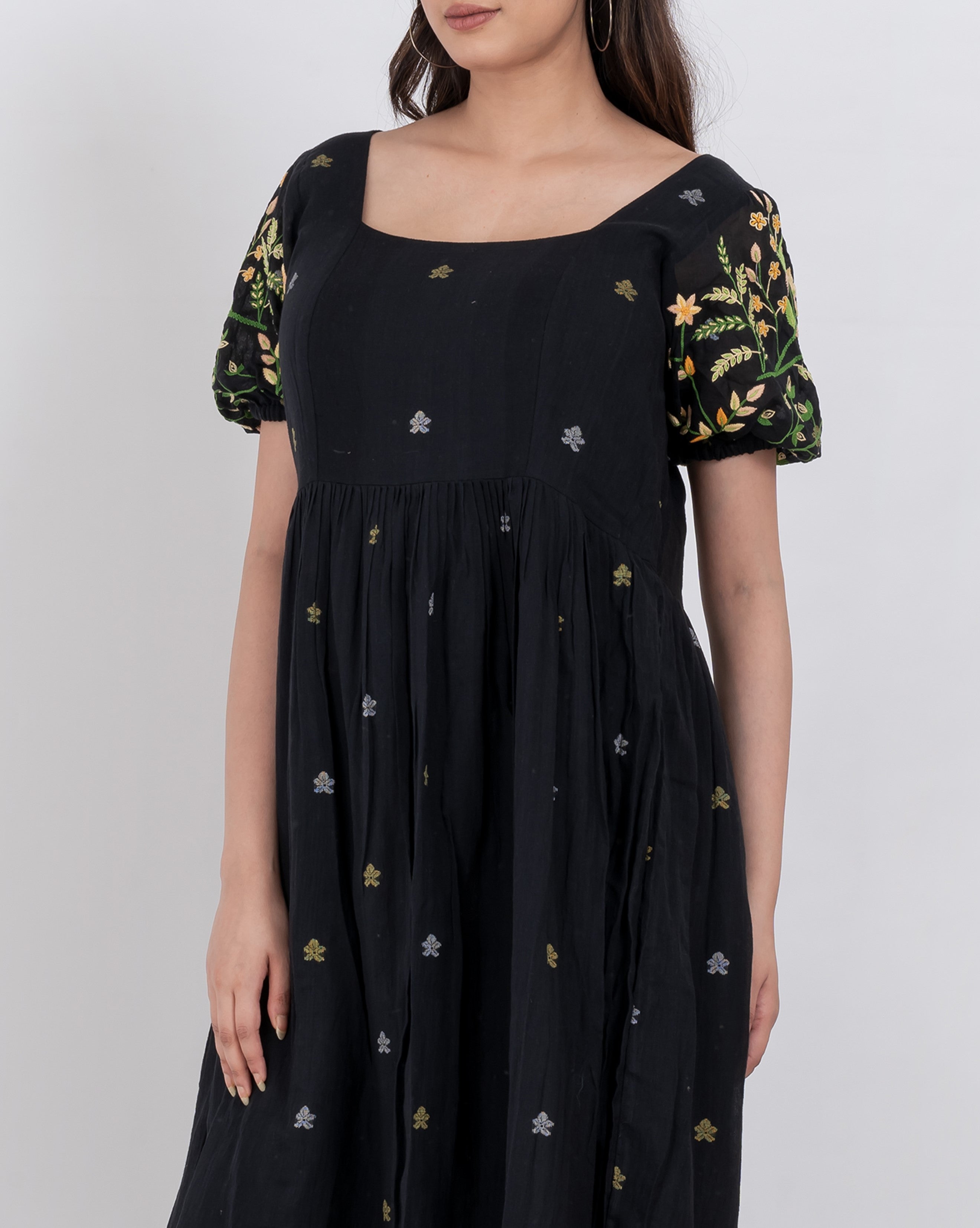 Detailed shot of the floral embroidery and square neckline of the handwoven cotton dress.