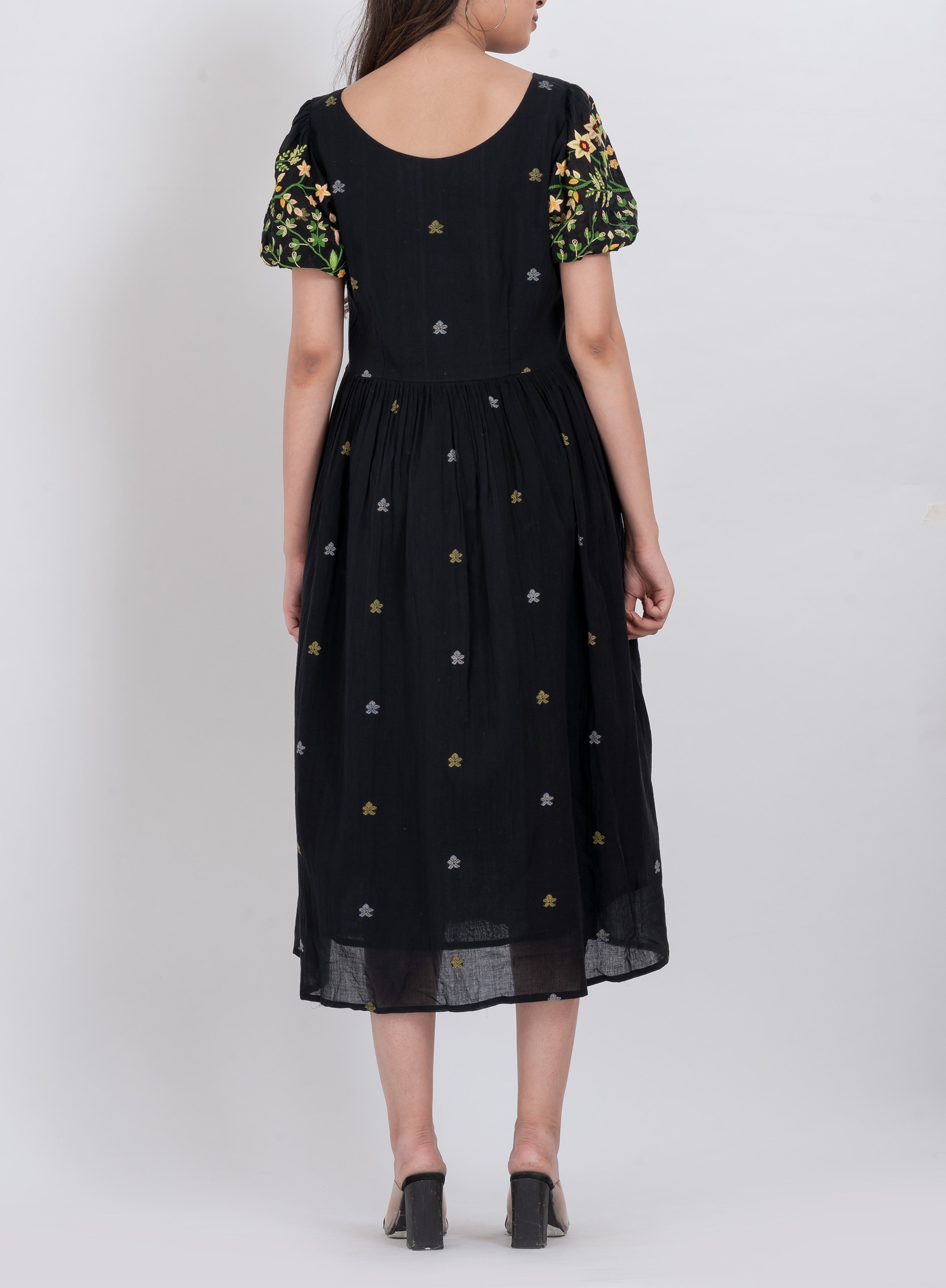 Close-up view of the puffed short sleeves and floral embroidery of a handwoven cotton dress.