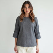 Woman wearing a gray blouse with a plain background