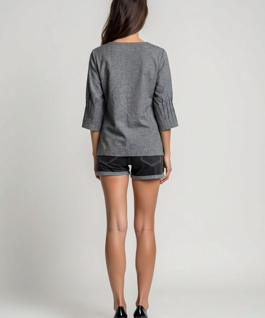 Woman wearing a gray top and black shorts on a plain background