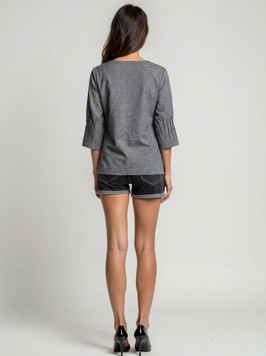 Woman wearing a gray top and black shorts on a plain background