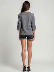 Woman wearing a gray top and black shorts on a plain background