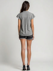 Woman wearing a gray short-sleeve shirt and black shorts on a plain background