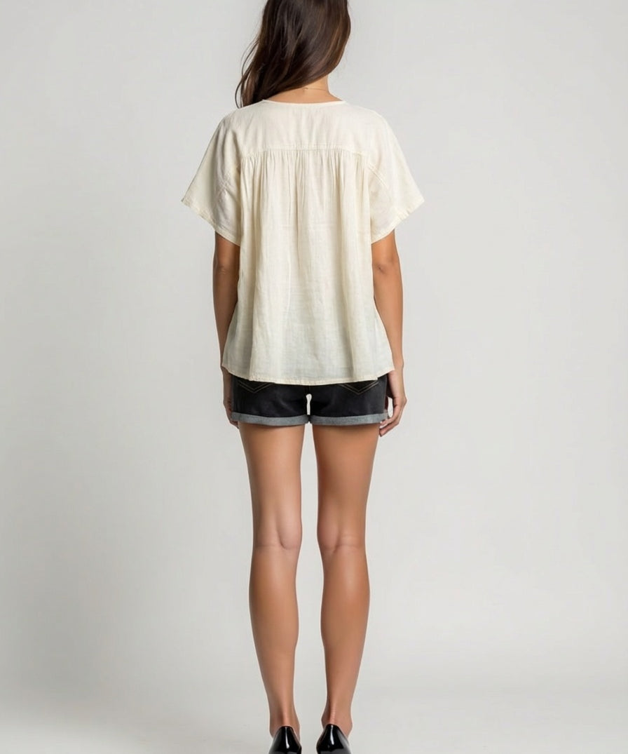 Person wearing a white blouse and black shorts on a plain background