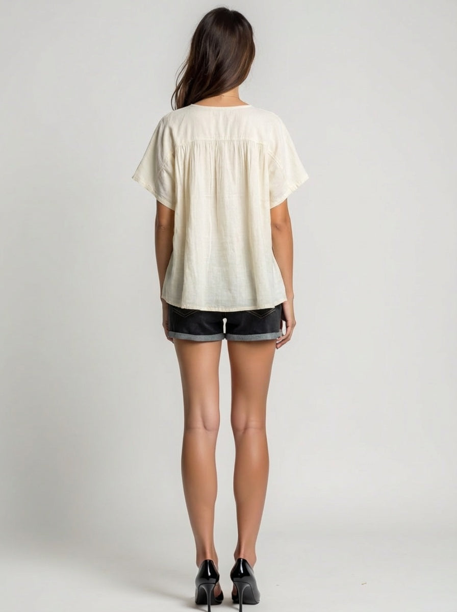 Person wearing a white blouse and black shorts on a plain background
