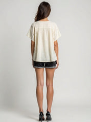 Person wearing a white blouse and black shorts on a plain background
