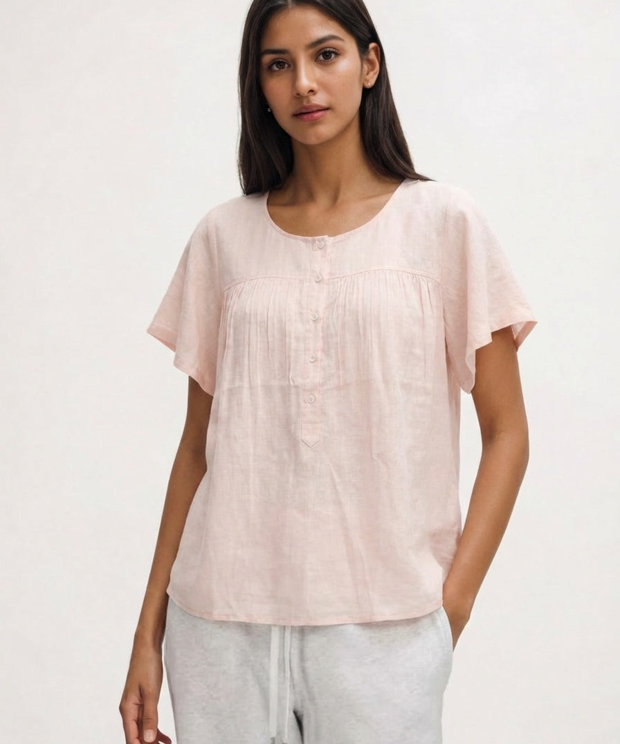 Woman wearing a light pink blouse with short sleeves on a white background