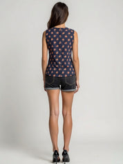 Woman wearing a sleeveless navy top with pink floral pattern and black shorts on a white background
