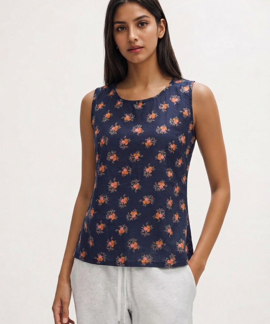 Woman wearing a navy sleeveless top with orange floral pattern on a white background