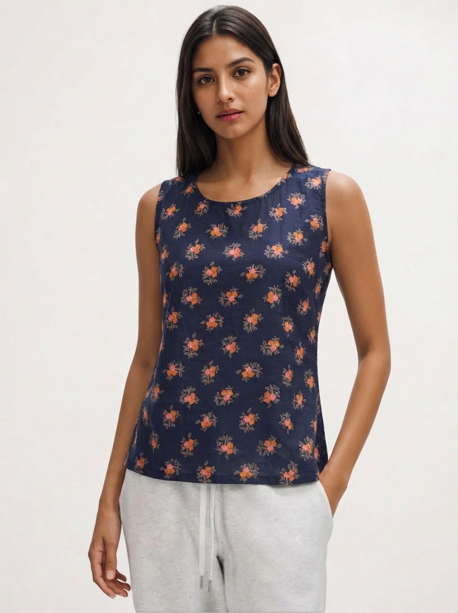 Woman wearing a navy sleeveless top with orange floral pattern on a white background