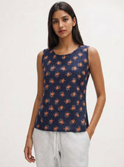 Woman wearing a navy sleeveless top with orange floral pattern on a white background