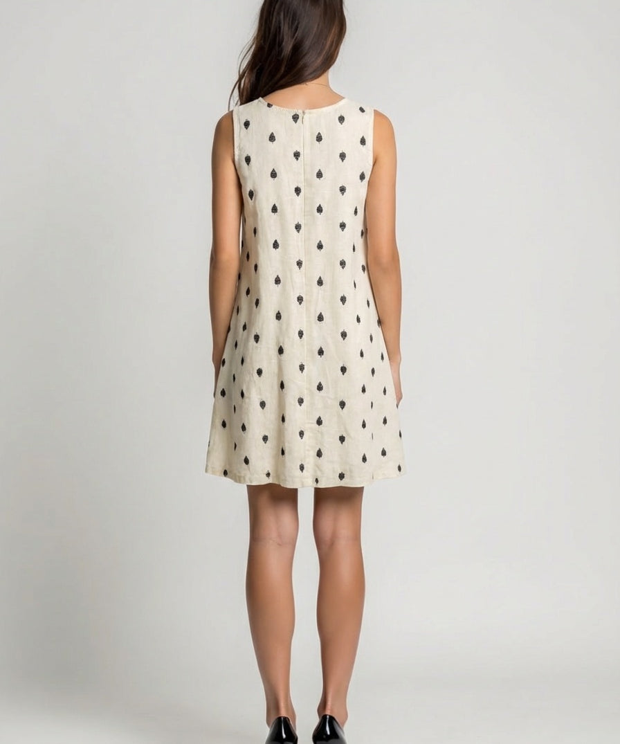 Woman wearing a sleeveless dress with black pattern on a plain background