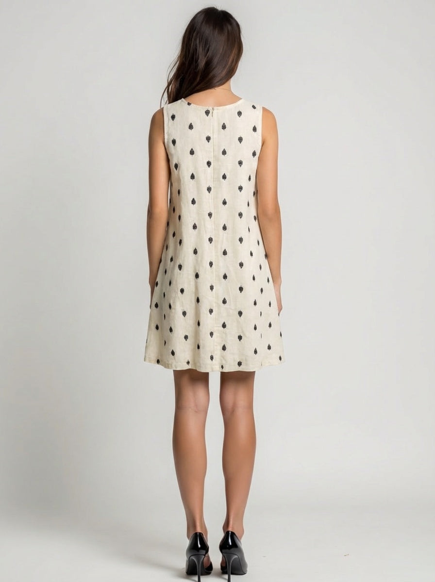 Woman wearing a sleeveless dress with black pattern on a plain background