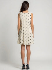 Woman wearing a sleeveless dress with black pattern on a plain background
