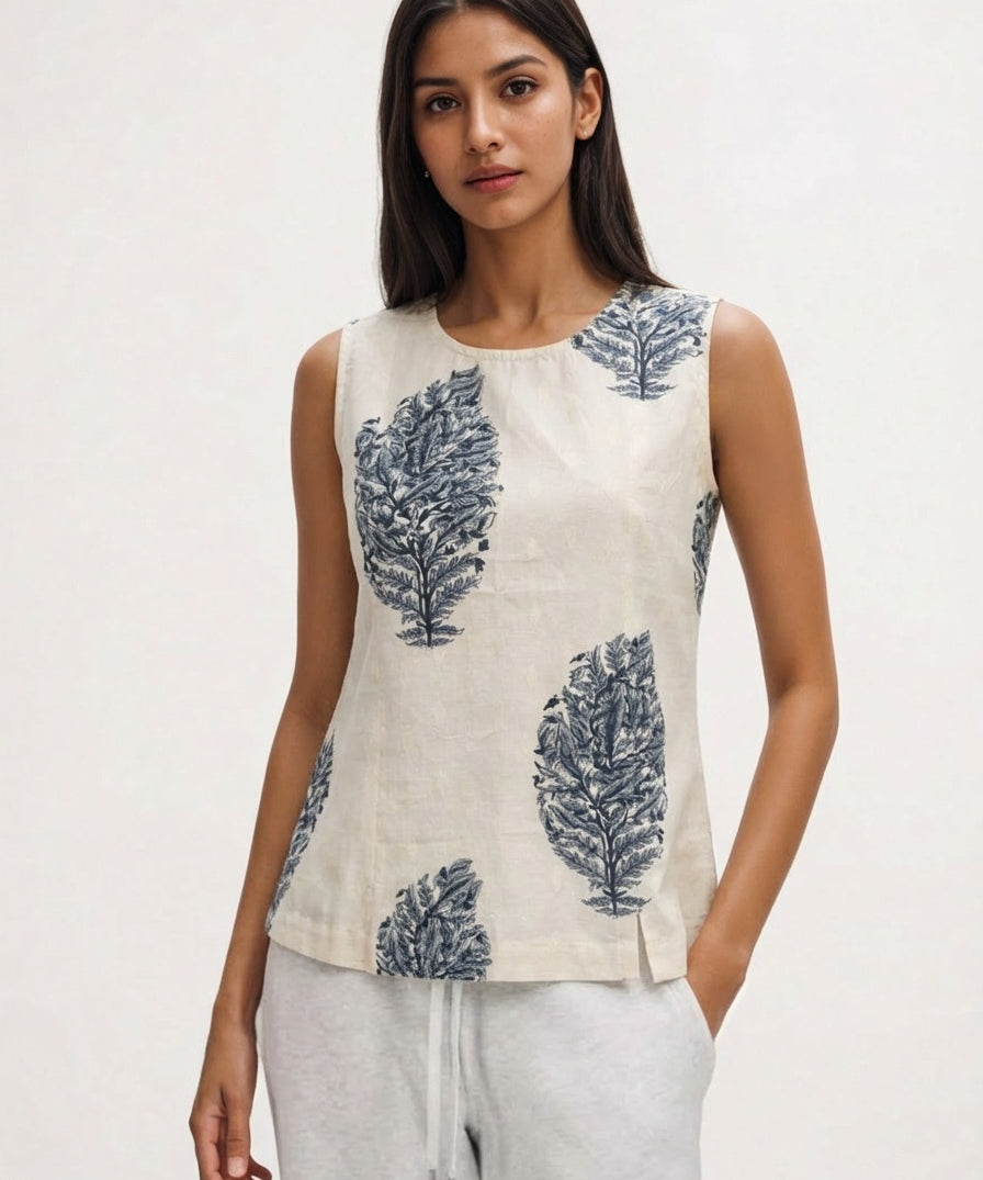 Woman wearing a sleeveless top with leaf pattern on a plain background