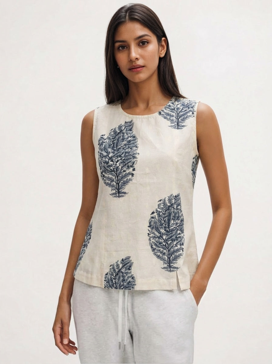 Woman wearing a sleeveless top with leaf pattern on a plain background
