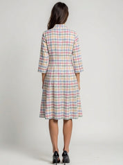 Woman wearing a plaid dress with a neutral background