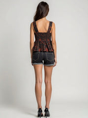 Woman wearing a patterned top and denim shorts on a plain background