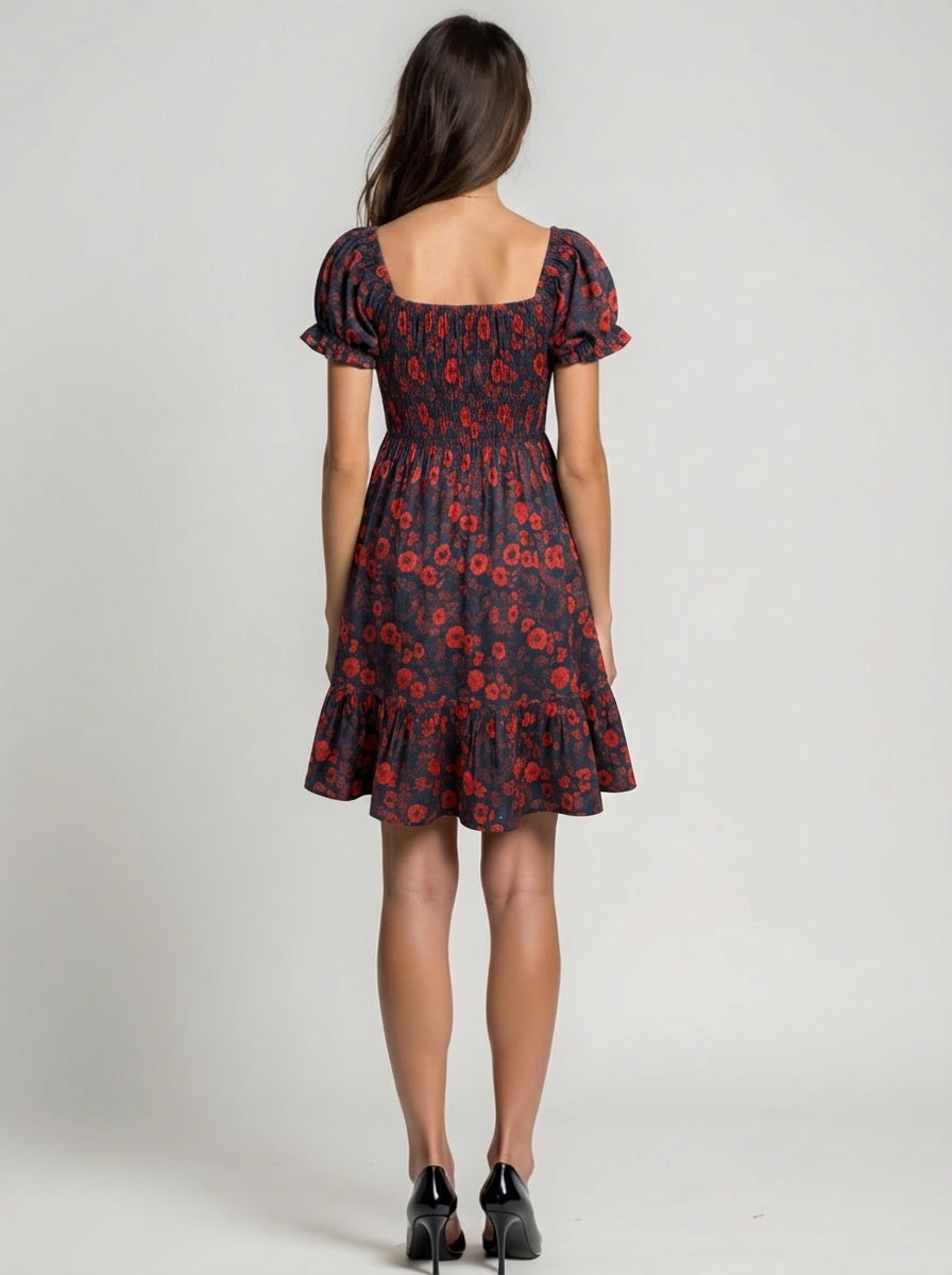 Woman wearing a black dress with red floral pattern on a plain background